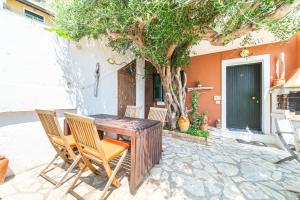 a wooden table and chairs in front of a house at Athena's Veranda magestic views in Glyfada beach of Corfu by New Era in Glyfada