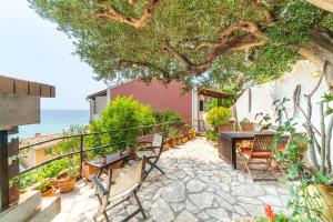 a patio with a table and chairs under a tree at Athena's Veranda magestic views Home 97 in Glyfada of Corfu by New Era in Glyfada