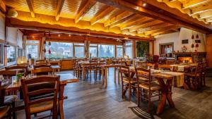 un restaurante con mesas y sillas de madera y ventanas en Hôtel - Restaurant Le Couchetat en La Bresse