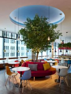 a lobby with a red couch and tables and a tree at citizenM Austin Downtown in Austin