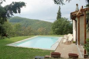 a swimming pool with lounge chairs next to a house at Villa Votanidi by VacaVilla in Borgo San Lorenzo