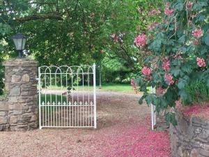 a white gate in a garden with pink flowers at Bellfry at Old Boley in Wexford