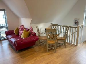 a living room with a red couch and a table at Debussys Guest House in Saffron Walden