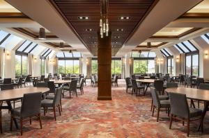 un comedor con mesas, sillas y ventanas en Hilton DFW Lakes Executive Conference Center, en Grapevine