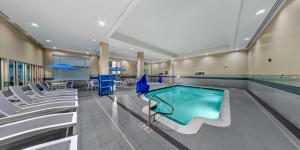a swimming pool in a building with chairs and a pool at Hilton Garden Inn Ithaca in Ithaca