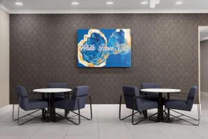 4 mesas y sillas en una sala de espera con una pintura en Homewood Suites by Hilton York en York