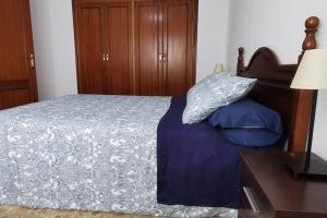 een slaapkamer met een bed met blauwe lakens en een tafel bij Apartamento en la Cala del Moral in Cala del Moral