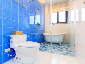 een blauwe betegelde badkamer met een toilet en een bad bij Elegance House in Wujie