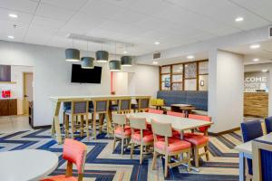 Hampton Inn Mobile-I-10/Bellingrath Gardens في تيلمانز كورنر: غرفة طعام مع طاولات وكراسي وتلفزيون