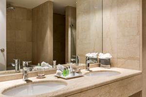 a bathroom with two sinks and a large mirror at NH Collection Brussels Grand Sablon in Brussels