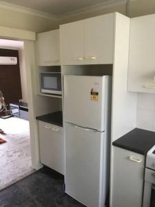 una cucina con armadietti bianchi e frigorifero bianco di Self contained 2 bedroom unit a Williamstown