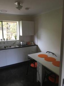 a kitchen with white cabinets and a table with two chairs at Self contained 2 bedroom unit in Williamstown