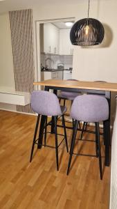 a dining room table with two purple chairs and a kitchen at Mysigt Stadsoas: En Modern lägenhet med 2 sovrum in Gothenburg