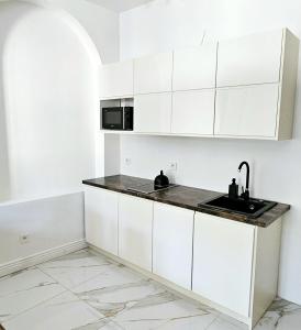 a white kitchen with a sink and a microwave at Pawia Apartments Centrum in Krakow