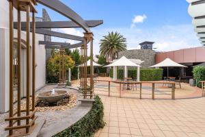 a courtyard with a fountain and tables and umbrellas at Quality Hotel Taylors Lakes in Taylors Lakes