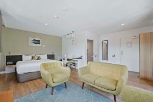 um quarto com uma cama, uma cadeira e uma secretária em The Kingsford Brisbane Airport, Ascend Hotel Collection em Brisbane