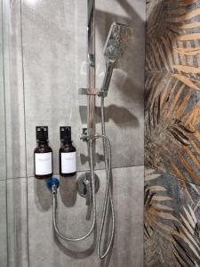 um chuveiro com duas garrafas de óleos essenciais numa parede em Le Moire Apartments em Ercolano