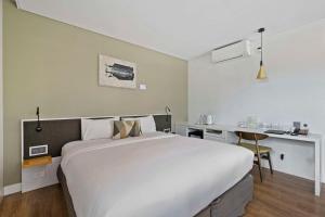 a bedroom with a large white bed and a desk at The Kingsford Brisbane Airport, Ascend Hotel Collection in Brisbane