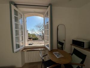 a room with a table and an open window at Studio Liège, vue mer au village de Bormes les Mimosas in Bormes-les-Mimosas