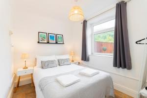a bedroom with a white bed and a window at The Trail by Afan Valley Escapes in Cymmer