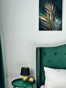a green bedroom with a bed and a table with a lamp at KOA - Moon Penthouse in Braşov
