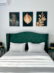 una camera da letto con testiera verde e quattro immagini sul muro di KOA - Moon Penthouse a Braşov