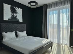 een slaapkamer met een groot bed en een groot raam bij KOA - Moon Penthouse in Braşov