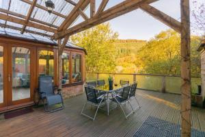 una terrazza in legno con tavolo e sedie. di The TRAIL Special Apartment In Afan Forest Bike Park By StayStaycations a Cymmer