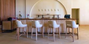 four white bar stools in front of a counter at Liwa Hotel in Mezairaa