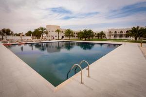 a swimming pool in a resort with palm trees at Liwa Hotel in Mezairaa