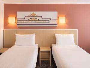 duas camas num quarto com luzes na parede em Mercure Newcastle em Newcastle