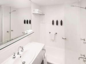 a white bathroom with a sink and a shower at Mercure Newcastle in Newcastle