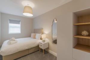 a bedroom with a white bed and a mirror at Stylish Windsor Getaway w/ Balcony - Free Parking in Windsor
