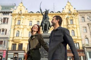 un hombre y una mujer caminando delante de una estatua en art'otel Zagreb, Powered by Radisson Hotels en Zagreb