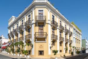 un edificio amarillo con balcones en una calle en GRAN HOTEL EUROPA TRADEMARK COLLECTION by WYNDHAM, en Santo Domingo