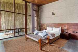 a bedroom with a bed and a large window at Sanctuary Resort, Chitwan National Park, Nepal in Chitwan