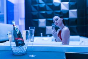a woman sitting in a bath tub with a bottle of champagne at Kreart Suite & Rooms B&B in Crotone