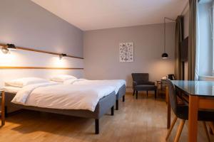 a bedroom with two beds and a desk and a table at Best Western Plus Park City Solna in Solna