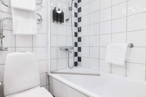 a white bathroom with a toilet and a bath tub at Best Western Plus Park City Solna in Solna