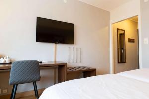 a bedroom with a desk with a television and a chair at Best Western Plus Park City Solna in Solna