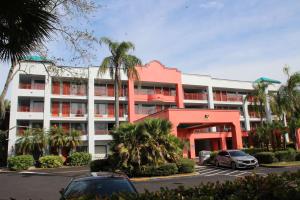 Un edificio rojo y blanco con autos estacionados en un estacionamiento. en Boca Suites Deerfield Beach; SureStay Collection by BW, en Deerfield Beach