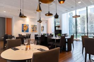 un restaurante con mesas, sillas y ventanas grandes en Best Western Plus Park City Malmö, en Malmö