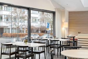 Best Western Plus Park City Hammarby Sjöstad في ستوكهولم: مطعم بطاولات وكراسي ونافذة كبيرة