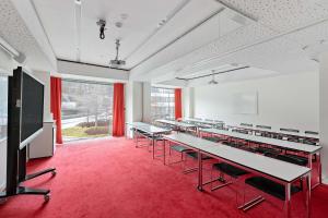 ein leeres Klassenzimmer mit Tischen und einem großen Bildschirm in der Unterkunft Best Western Plus Park City Hammarby Sjöstad in Stockholm