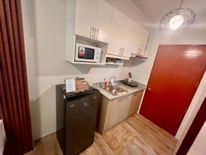 a small kitchen with a sink and a microwave at Mesavirre Garden Residence in Bacolod