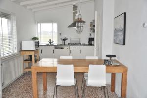 - une cuisine avec une table en bois et des chaises blanches dans l'établissement De Blenck 7, à Callantsoog