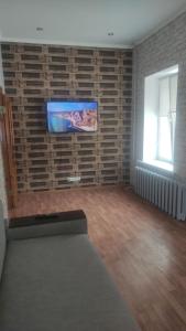 uma sala de estar com uma televisão de ecrã plano numa parede de tijolos em Cozy apartment near city center on Peremogy Avenue 44, bus and railway station nearby em Chernigov