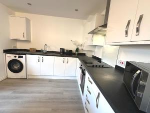 a kitchen with white cabinets and a black counter top at Rosebank Court by Blue Skies Stays in Stockton-on-Tees