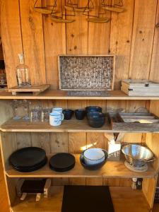 une étagère en bois avec des plaques et des bols noirs dans l'établissement La cabane du Broustic, à Andernos-les-Bains