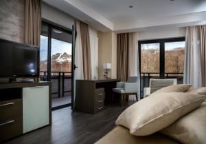 a bedroom with a bed and a television and a desk at Hotel Stara Planina in Ćuštica